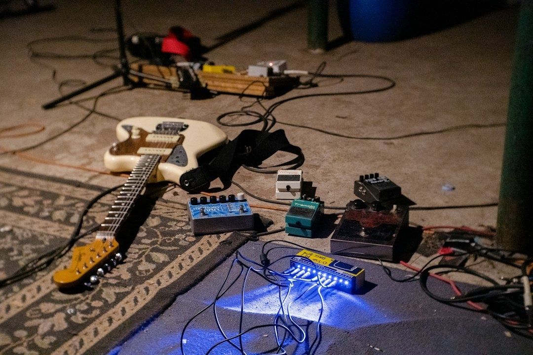 E-Gitarre mit mehreren Effektpedalen und Kabeln auf einem Bühnenboden